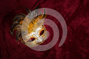 Venetian carnival mask on a draped red velvet theater curtain