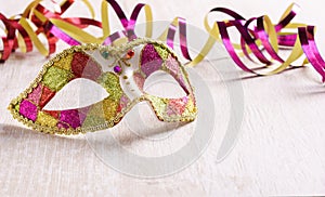 Venetian carnival mask with paper streamer on bright wood background photo