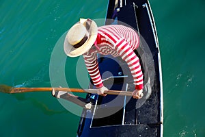 Venetian gondolier with hat rowing on gondola on grand canal in Venice in Italy