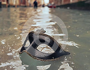 Venetian mask floating on canal at the end of Venice Carnival