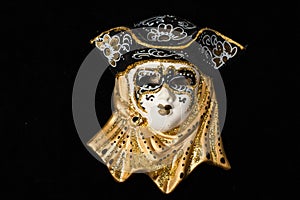 Venetian masks of white and black ceramic ornament with golden or gold highlights. Black background