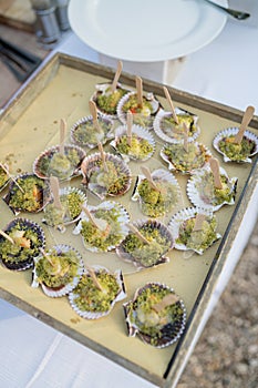 Venetian-style scallops stand on a tray with wooden spatulas. Top view photo