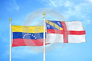 Venezuela and Herm two flags on flagpoles and blue sky