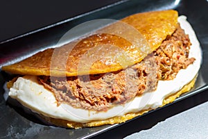 Venezuelan Cachapa with Pulled Meat on Black Plate in Restaurant