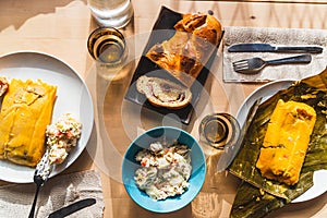 Venezuelan christmas food display on table with traditional hallacas, pan de jamon or ham bread, and mixed salad, with cutlery and