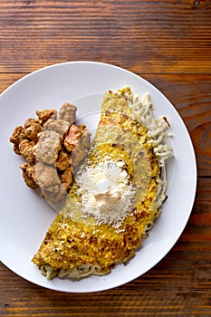 VENEZUELAN FOOD. Corn CACHAPA with cheese and fried pork - cochino frito. Wooden background, top view