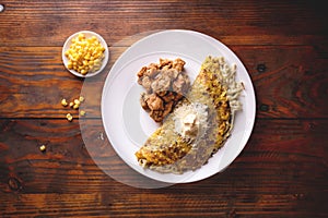 VENEZUELAN FOOD. Corn CACHAPA with cheese and fried pork - cochino frito. Wooden background, top view