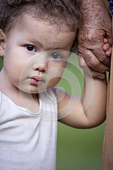 Venezuelan toddler boy holding elderly`s hand