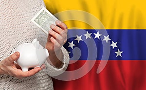 Venezuelan woman with money bank on the background of Venezuela flag. Dotations, pension fund, poverty, wealth, retirement concept