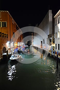 Venice canal at night in Italy with boats moored near buildings