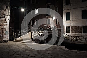 Venice canal view at night with bridge and historical buildings