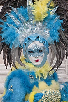 Venice Carnival figure wearing colorful blue, yellow and black costume and venetian mask Venice Italy