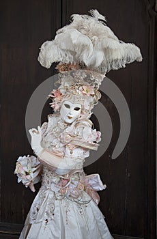 Venice Carnival figure wearing colourful peach & white costume and venetian mask Venice Italy