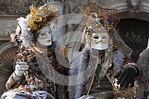 Venice Carnival figures wearing colourful brown and gold costumes and venetian masks Venice