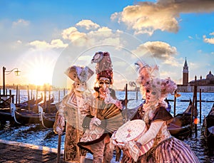 Venice with carnival masks against colorful sunrise in Italy