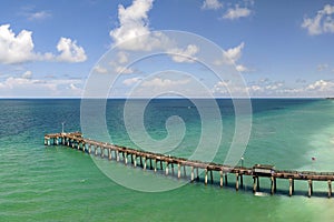 Venice fishing pier in Florida on sunny summer day. Bright seascape with surf waves crashing on sandy beach