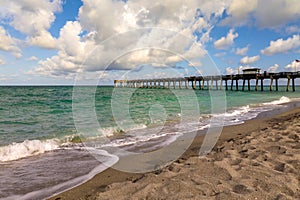 Venice fishing pier in Florida on sunny summer day. Bright seascape with surf waves crashing on sandy beach