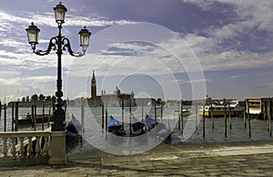 Venice, gondolas or gondole, street light and San Giorgio Maggiore church landmark on background. Italy, Europe