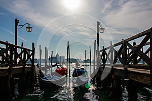 Venice italian city view with gondolas parked at seashore, channels and bridges, sea and clouds sky landscape at sunny day in Ital