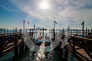 Venice italian city view with gondolas parked at seashore, channels and bridges, sea and clouds sky landscape at sunny day in Ital