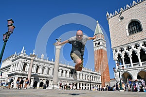 VENICE, ITALY - APRIL 19, 2021: man jump near saint mark bell tower and palace of Doge in Venice, Italy