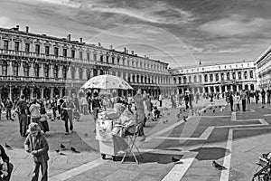 People visit Piazza San Marco square in Venice, Italy with doves flying around