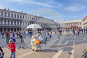 People visit Piazza San Marco square in Venice, Italy with doves flying around