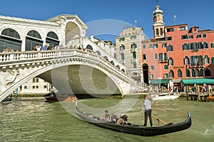 Tourists riding on Gondola under the Rialto Bridge on Canal Grande in Venice, Italy
