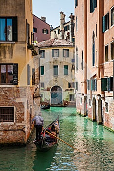 Tourists sailing in a gondola on the beautiful canals of Venice in an early spring day