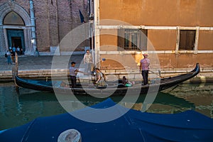 VENICE, ITALY - August 27, 2021: View of couple tourists entering gondola on canals of Venice