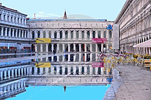 VENICE,ITALY Empty St Mark`s Square during a flood with beautiful water reflections of historical buildings on wet f