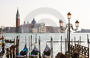 VENICE, ITALY - FEBRAURY 08, 2020: people on embankment look at Isola di San Giorgio Maggiore and gondolas.