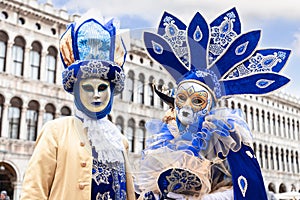 A couple of participants in the Venetian carnival in the original masks on Piazza San Marco