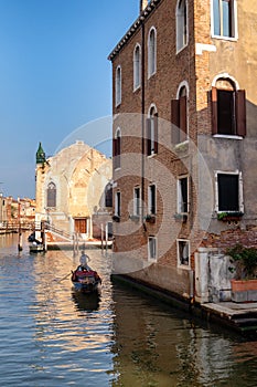 Venice, Italy. Gondolier rules a gondola on a narrow canal