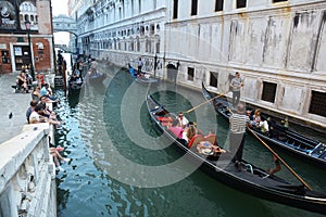 VENICE, ITALY - JULY 17, 2019 - Venetian gondolier punts gondola through narrow canal waters of Venice Italy