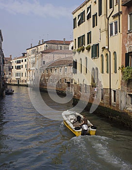 Traditional canal in Venice with motoboat crossing it