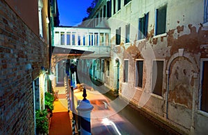 Venice, Italy: Narrow canal passing through building connected with a passage during night