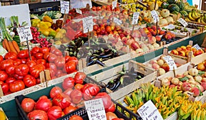 Venice, Italy - september 2016: Rialto fish markets. Fishmonger at work.Tablets with price of tomatoes, peaches, flowers, zucchini