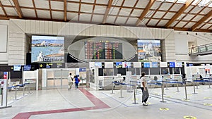 VENICE,ITALY.16 SEPTEMBER 2023.In Venice Airport, a small group lingers by the flight info board near quiet check-in counters