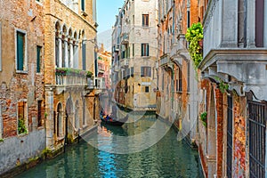 Venice, Italy. Venetian gondolier floating on gondola with tourists through green canal waters of Venice