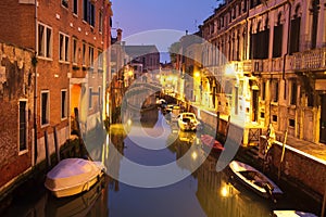 Venice night cityscape with boats in canal, Italy. Venice street illuminated lanterns