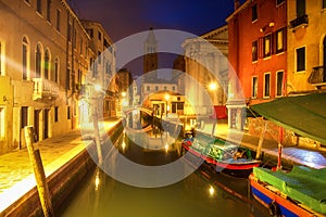 Venice at night, Italy. Beautiful view on narrow venetian canal with boats at night. Venezia illuminated by citylights