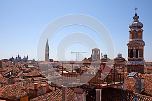 Venice roofs with typical wooden altana balcony, blue sky