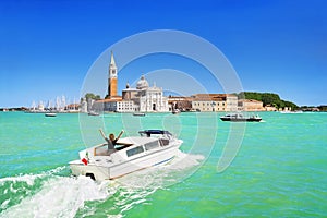 Venice seascape. Giudecca Canal and San Giorgio Maggiore island, Italy, Europe. Motor boat with Italian flag and woman up her