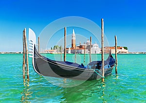 Venice seascape with gondola at wooden bricole mooring against famous San Giorgio Maggiore island and church in sunny day. View