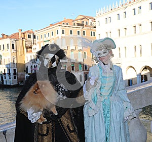 Venice, VE, Italy - February 13, 2024: couple of masked people and a dog on the rialto bridge during the carnival