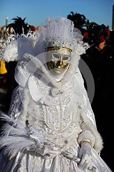Venice, VE, Italy - February 13, 2024: person with an ancient golden mask and embroidered white dress at the carnival