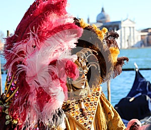Venice, VE, Italy - February 13, 2024: Venetian Mask at the Venice Carnival and sea of lagoon with St George Church