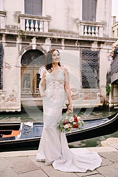 Venice wedding in Italy. A bride in a white dress, with a train, with a bouquet of white and red roses in her hands