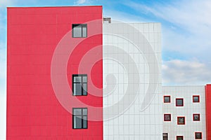 Ventilated facade of building. White-red wall of building with small windows. Fragment of modern residential building